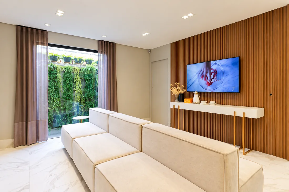 Sala com sofá claro, painel de madeira e janela para um jardim vertical